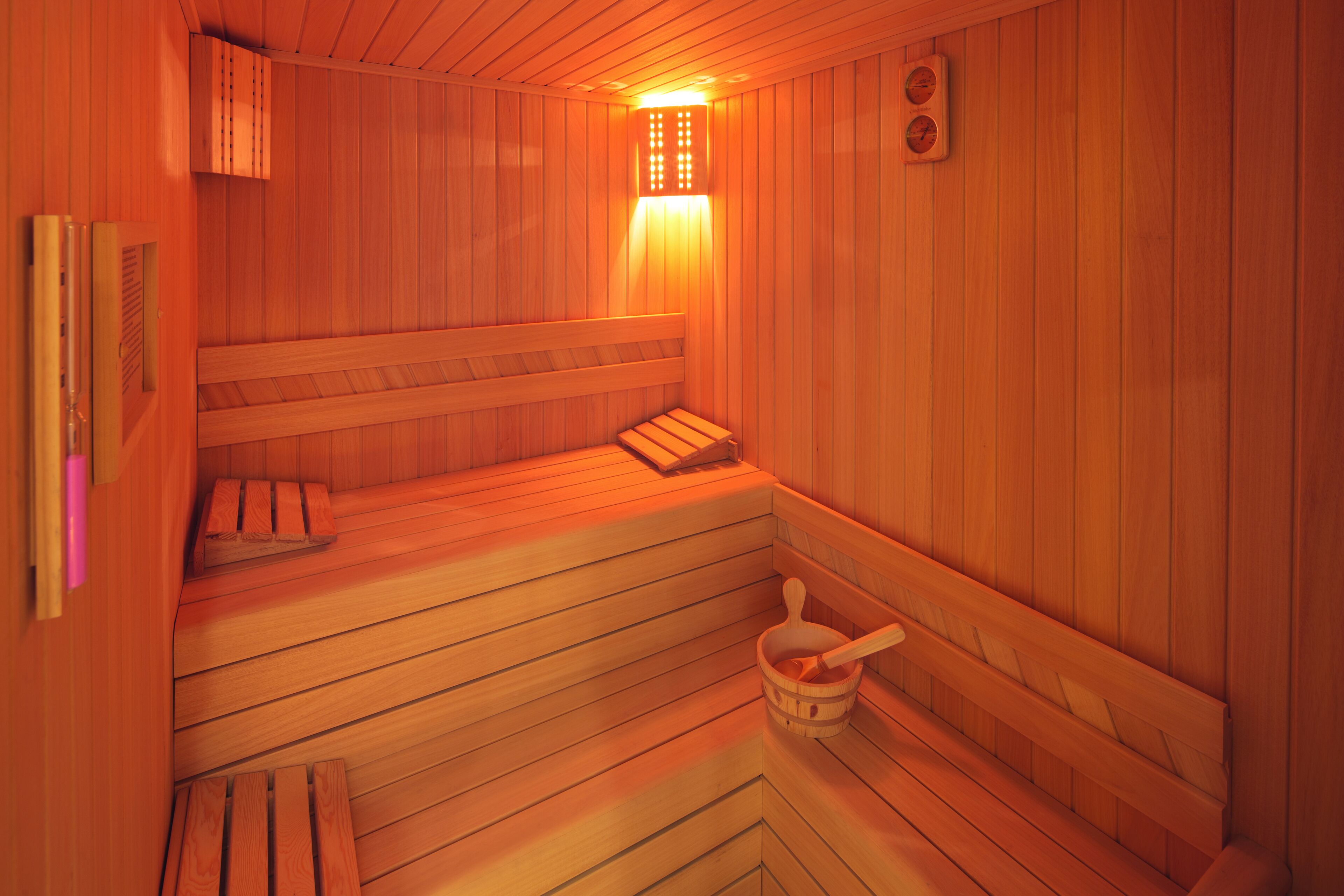 A wooden sauna with benches and a wooden bucket.