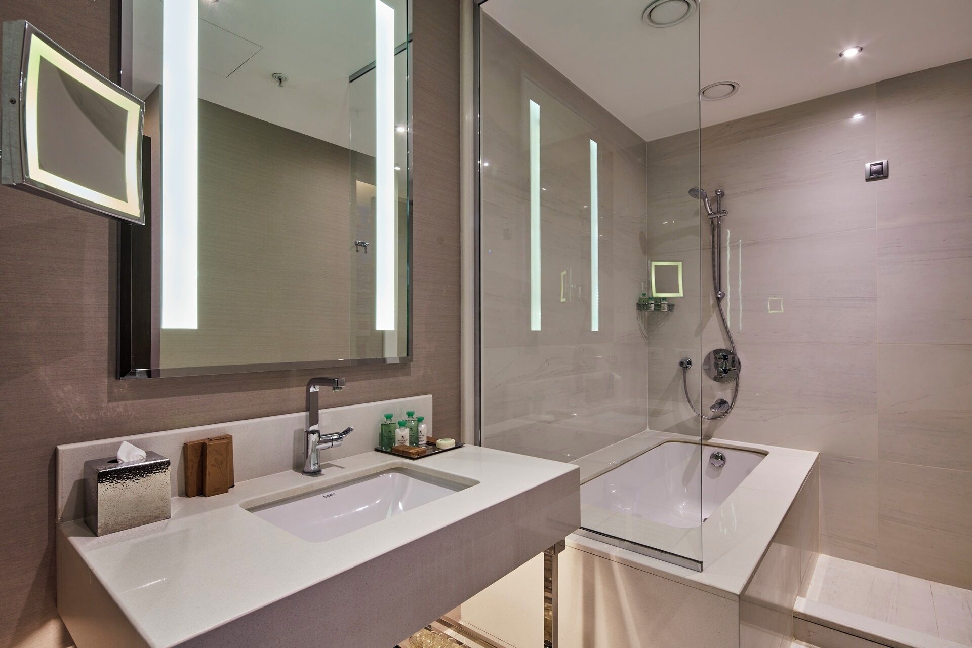 Un bagno moderno con due lavabi, uno specchio grande e una cabina doccia in vetro.