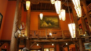 A rustic interior with wooden beams, a balcony, and a painting of a landscape.