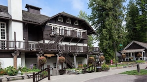 A traditional wooden building with a balcony, stairs, and hanging flower baskets.
