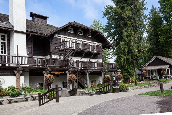 A traditional wooden building with a balcony, stairs, and hanging flower baskets. - Lake McDonald Lodge - Inside the Park (West Glacier)