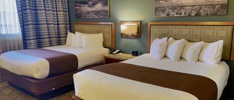 A hotel room with two beds, a patterned carpet, and two wall-mounted lamps.