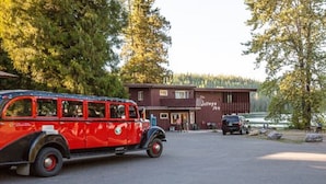 Un coche rojo antiguo estacionado frente a un edificio rústico con un letrero que dice "The Village".