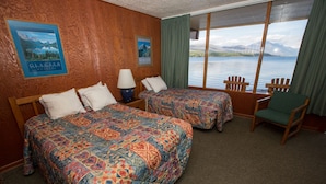 Una habitación con dos camas, una silla y vistas a un lago.