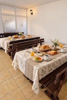 Una mesa de desayuno con mesas, bancos y una variedad de alimentos y bebidas.