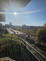 Un paisaje urbano con cielo despejado, edificios y una calle con coches estacionados.