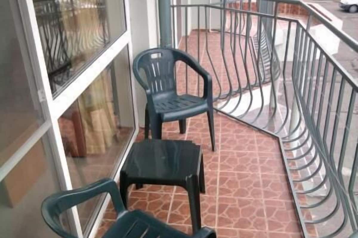 A balcony with two chairs and a small table, metal railings, and a tiled floor.
