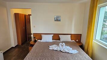 Una cama doble con un edredón estampado, un cabecero y una ventana con cortinas.