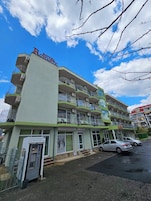 Un hotel de varios pisos con balcones, un estacionamiento y cielo despejado.