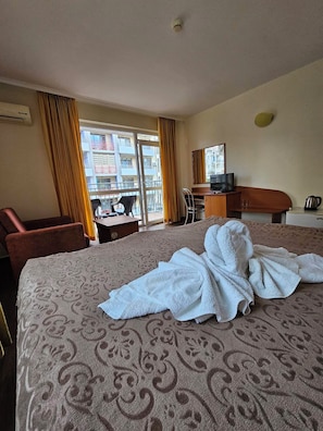 A hotel room with a bed, a desk, a chair, a television, and a view of the outside. - Family Hotel Romantic (Sunny Beach)