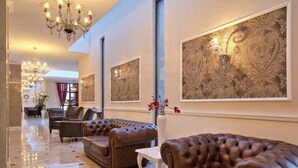 A spacious lobby with leather sofas, a chandelier, and large decorative wall panels. - White Rock Castle Suite Hotel & Wellness Club (Balchik)
