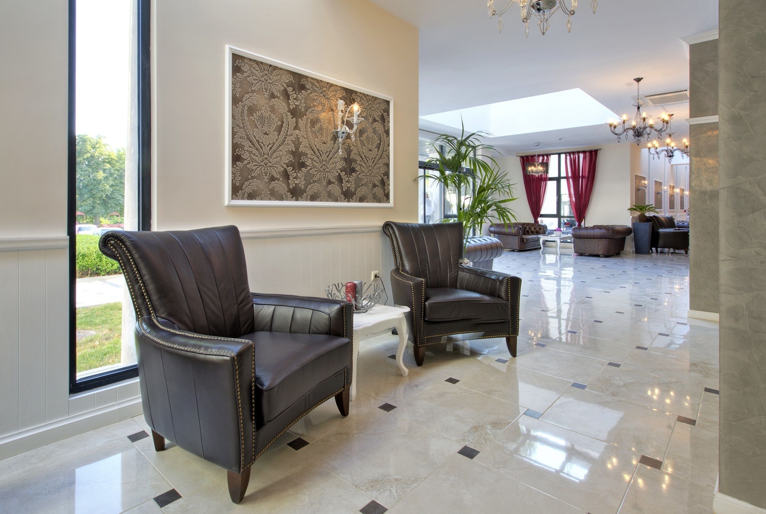 A spacious lobby with leather armchairs, a large abstract painting, and a chandelier.