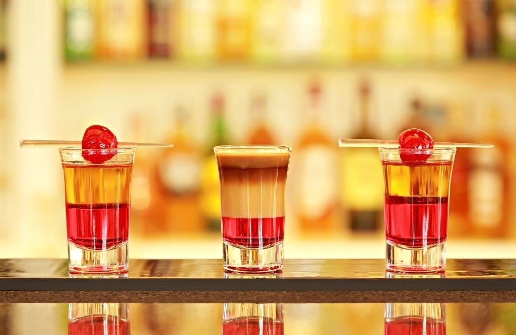 Three cocktails with a cherry garnish on a bar counter.