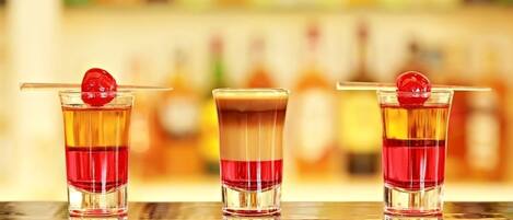 Three cocktails with a cherry garnish on a bar counter.