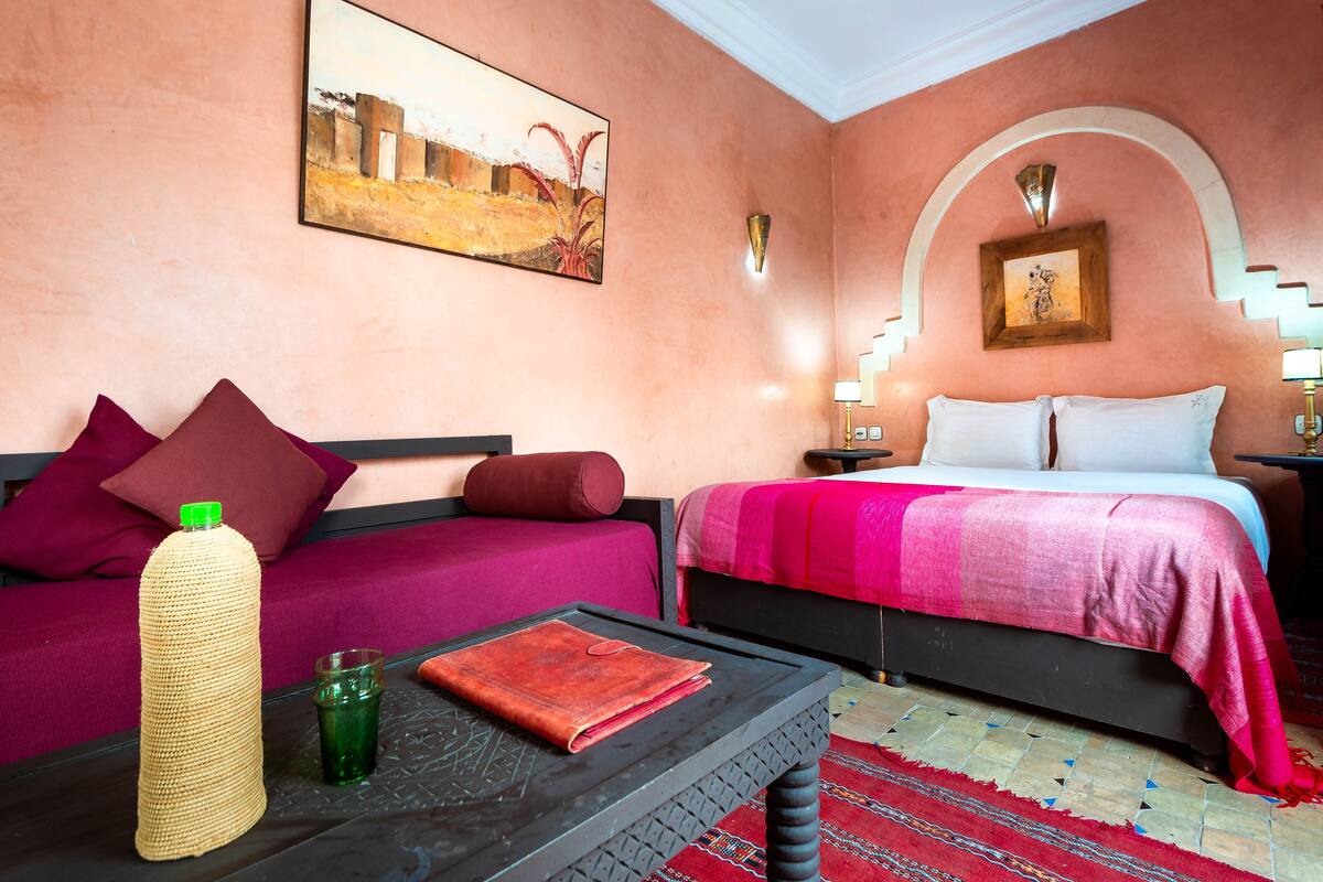 Une chambre d’hôtel avec deux lits, une table basse, une lampe et un tableau au mur.