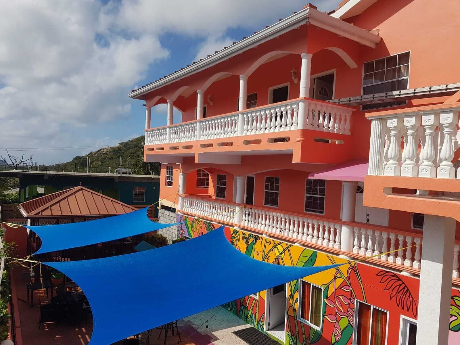Un immeuble à plusieurs étages doté de balcons, d’une fresque murale colorée et d’un auvent bleu.