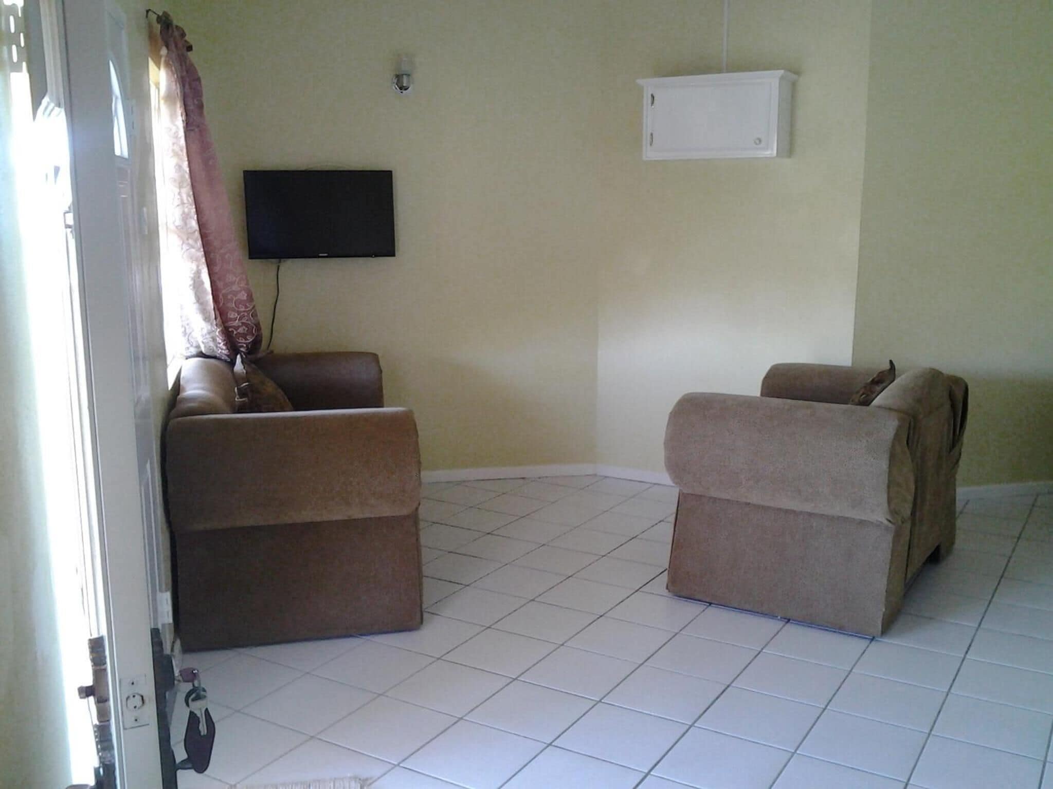 A room with two sofas, a flat-screen TV mounted on the wall, and a whiteboard.
