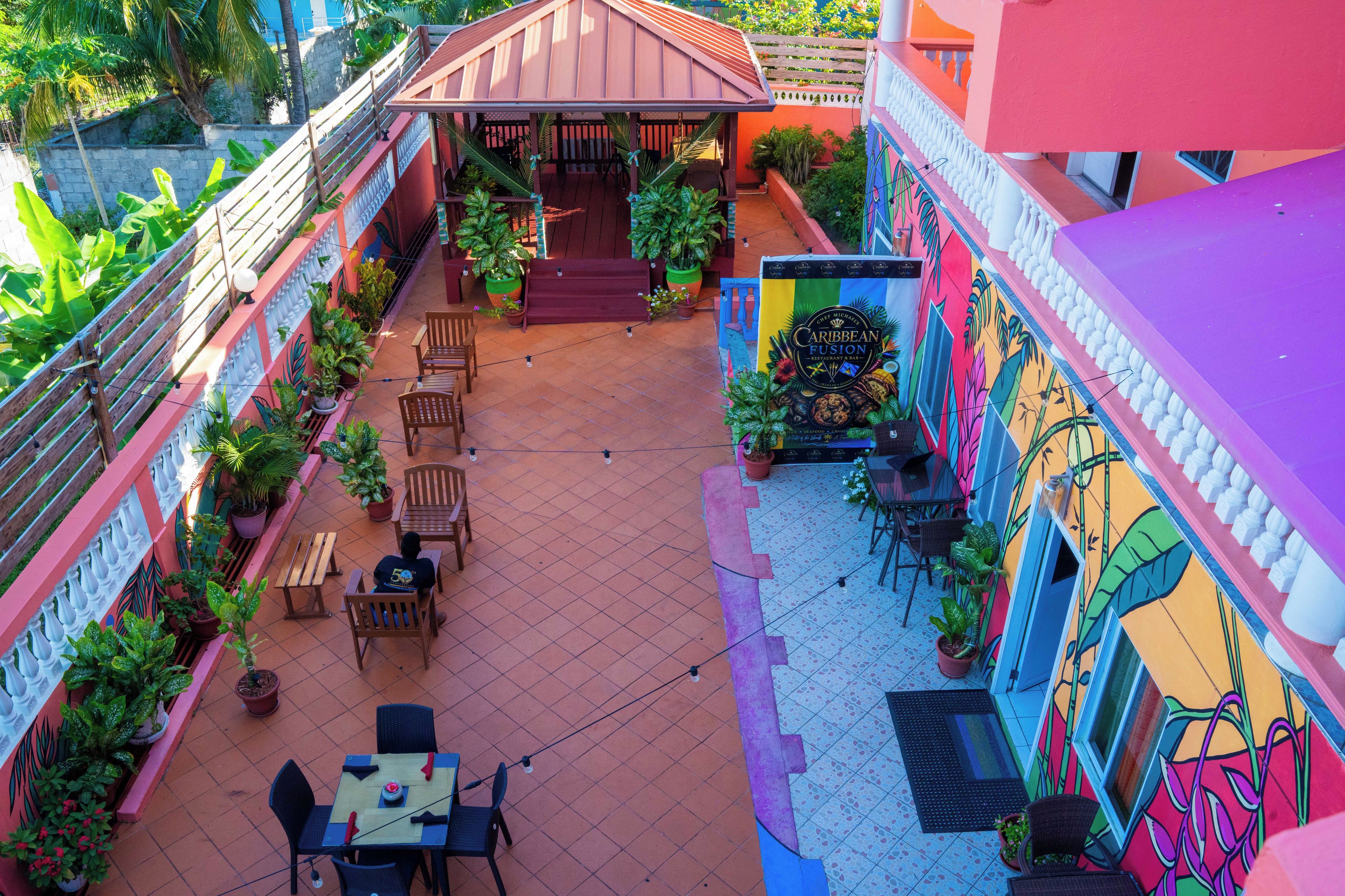Une terrasse sur le toit avec des espaces pour s’asseoir à l’extérieur, des plantes en pot et une fresque murale colorée.