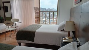A hotel room with a bed, a chair, a table, a lamp, and a phone on a nightstand. - Europa Hotel Boutique (Manizales)