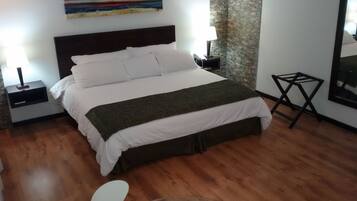 Una habitación de hotel con una cama, una mesita de noche, una lámpara, una pequeña mesa y un cuadro en la pared.