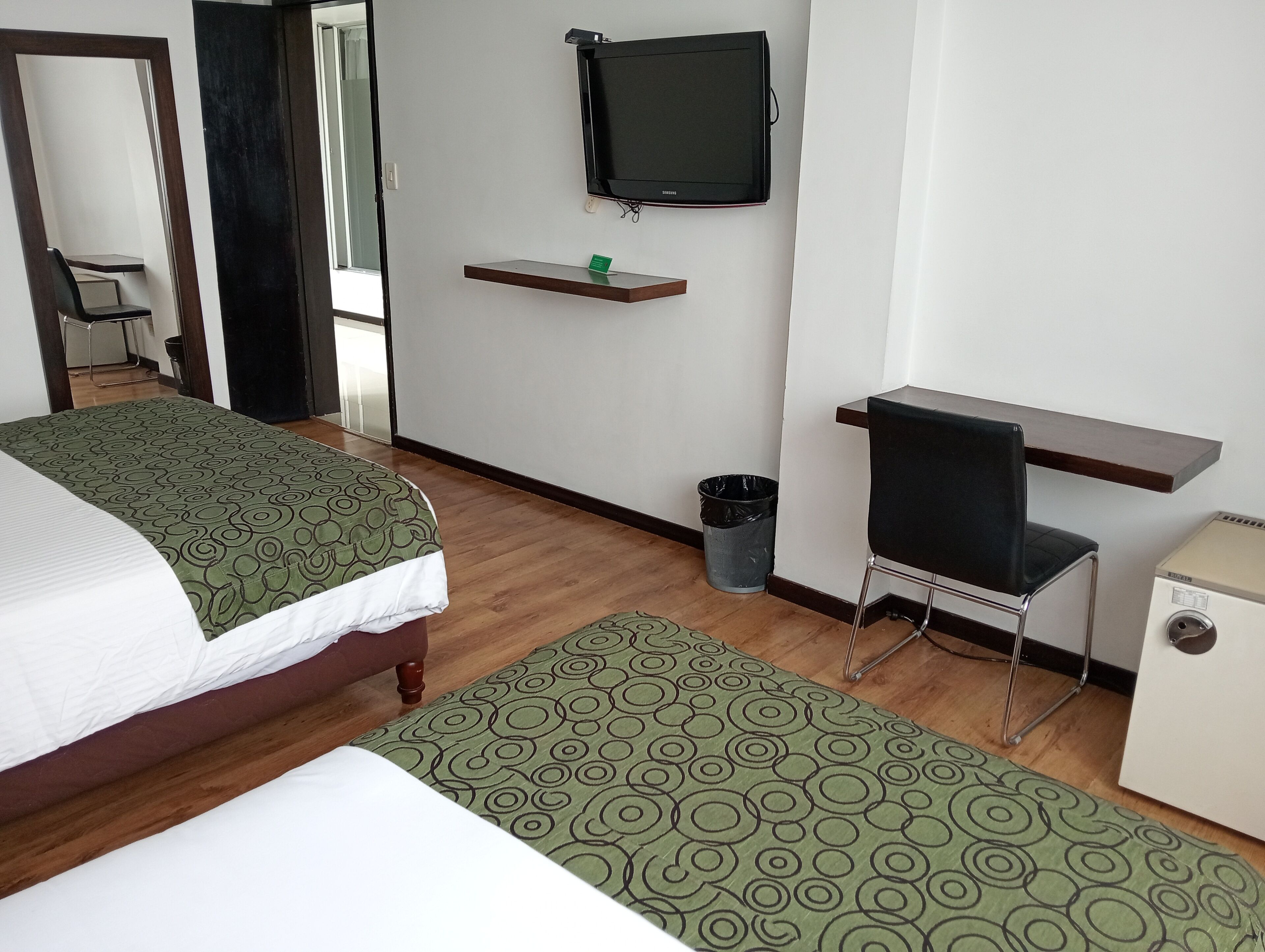 Une chambre d’hôtel équipée d’un lit, d’un bureau, d’une chaise, d’une télévision et d’une petite armoire.