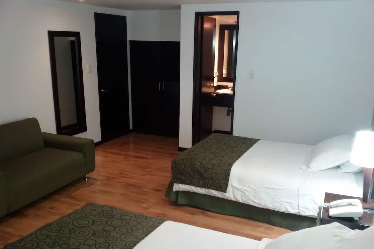 Ein Hotelzimmer mit einem Bett, einem Sofa, einem Spiegel und einer Tür zu einem Badezimmer.
