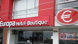 A Europa Hotel Boutique with a red and white facade, a glass entrance, and a visible currency symbol. - Europa Hotel Boutique (Manizales)