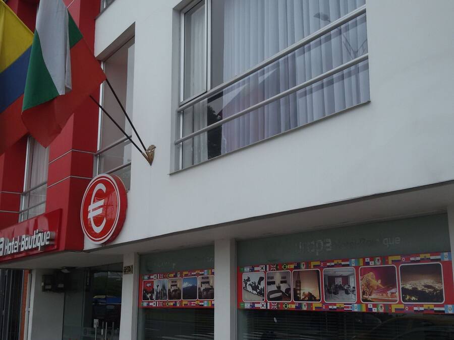 Ein Hotel mit roter und weißer Fassade, einer sichtbaren Flagge und einem Schild, das es als Boutique-Hotel kennzeichnet.