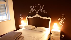 Una cama bien hecha con cabecera blanca, dos lámparas de noche y un edredón doblado sobre la cama.