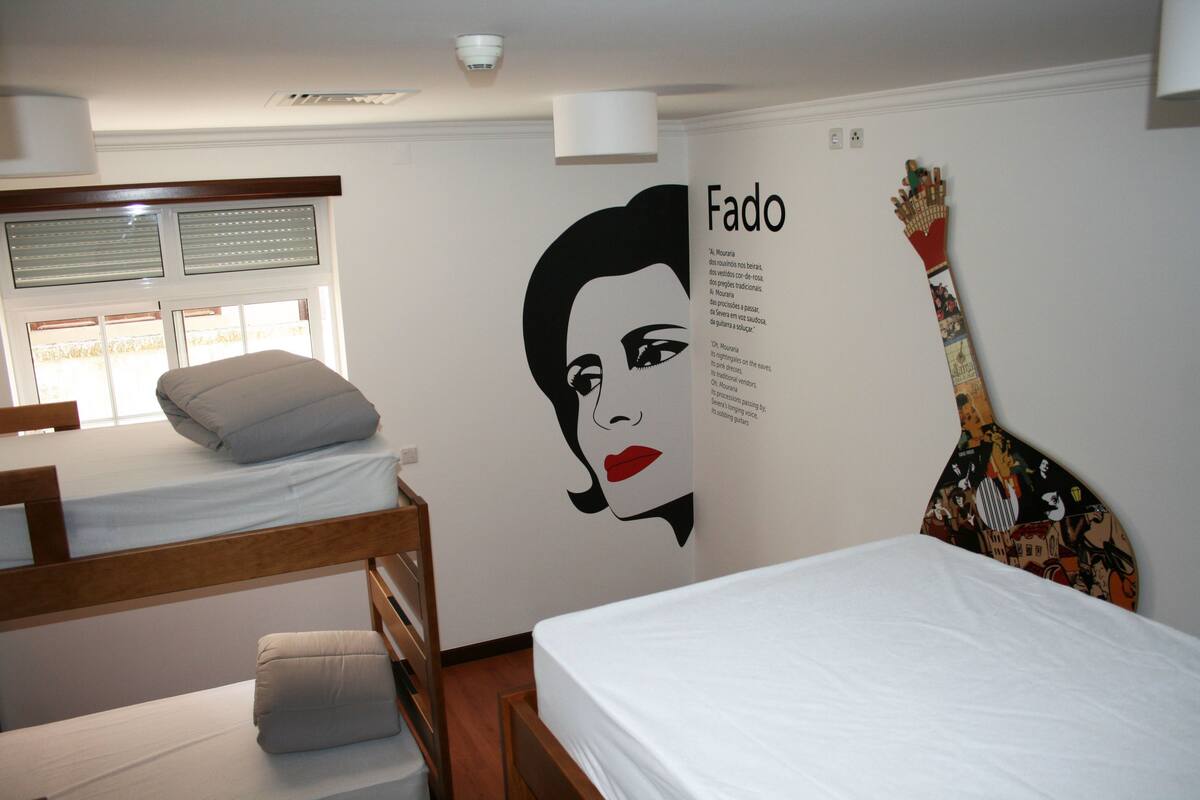 A room with bunk beds, a guitar wall art, and a poster of a woman with the name 'Fado'.