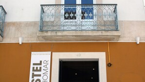 Un hostal con un cartel que dice "HOSTEL 2300 THOMAR" y un balcón con barandilla de metal.