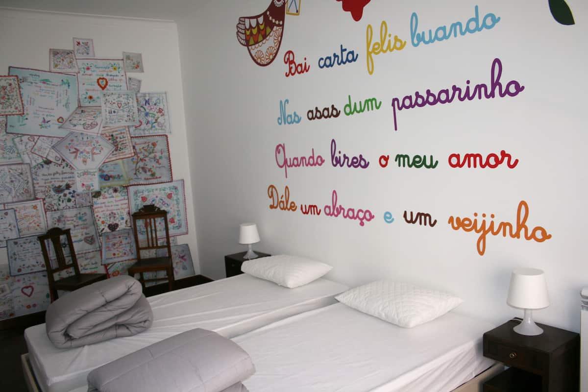 A bedroom with two beds, a wall decorated with colorful notes, and a wall clock.
