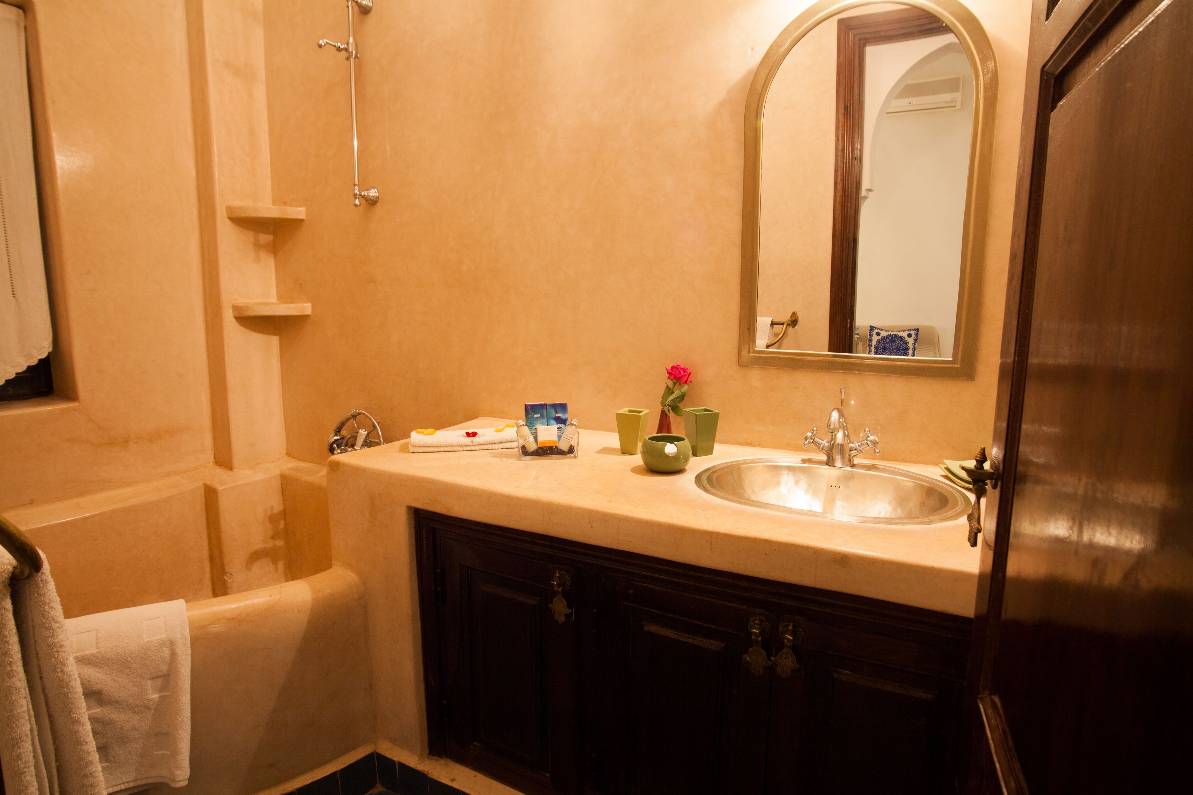 A bathroom with a bathtub, a sink, a mirror, and a vanity with cabinets.