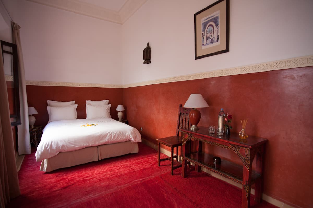 Habitación de hotel con una cama grande, una mesita de noche de madera con una lámpara y un cuadro enmarcado en la pared.