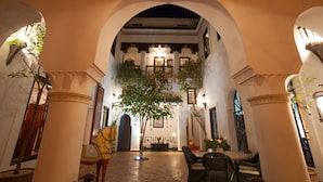 An indoor courtyard with arches, a central tree, and seating areas. - Riad Chergui (Marrakech)