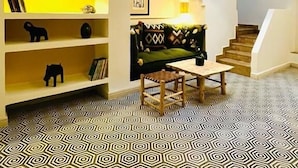 A modern interior with a geometric patterned floor, a staircase, and a bookshelf with decorative items. - Riad Chergui (Marrakech)