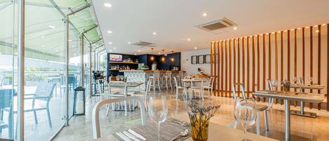 A modern restaurant with a bar area, dining tables, and chairs.