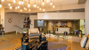 A modern lobby with a reception desk, seating area, and a staircase. - GHL San Lazaro Art Hotel (Cartagena)