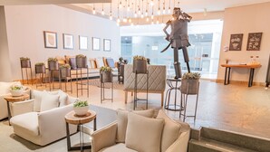 A modern hotel lobby with a sofa set, chairs, a statue, and potted plants. - GHL San Lazaro Art Hotel (Cartagena)