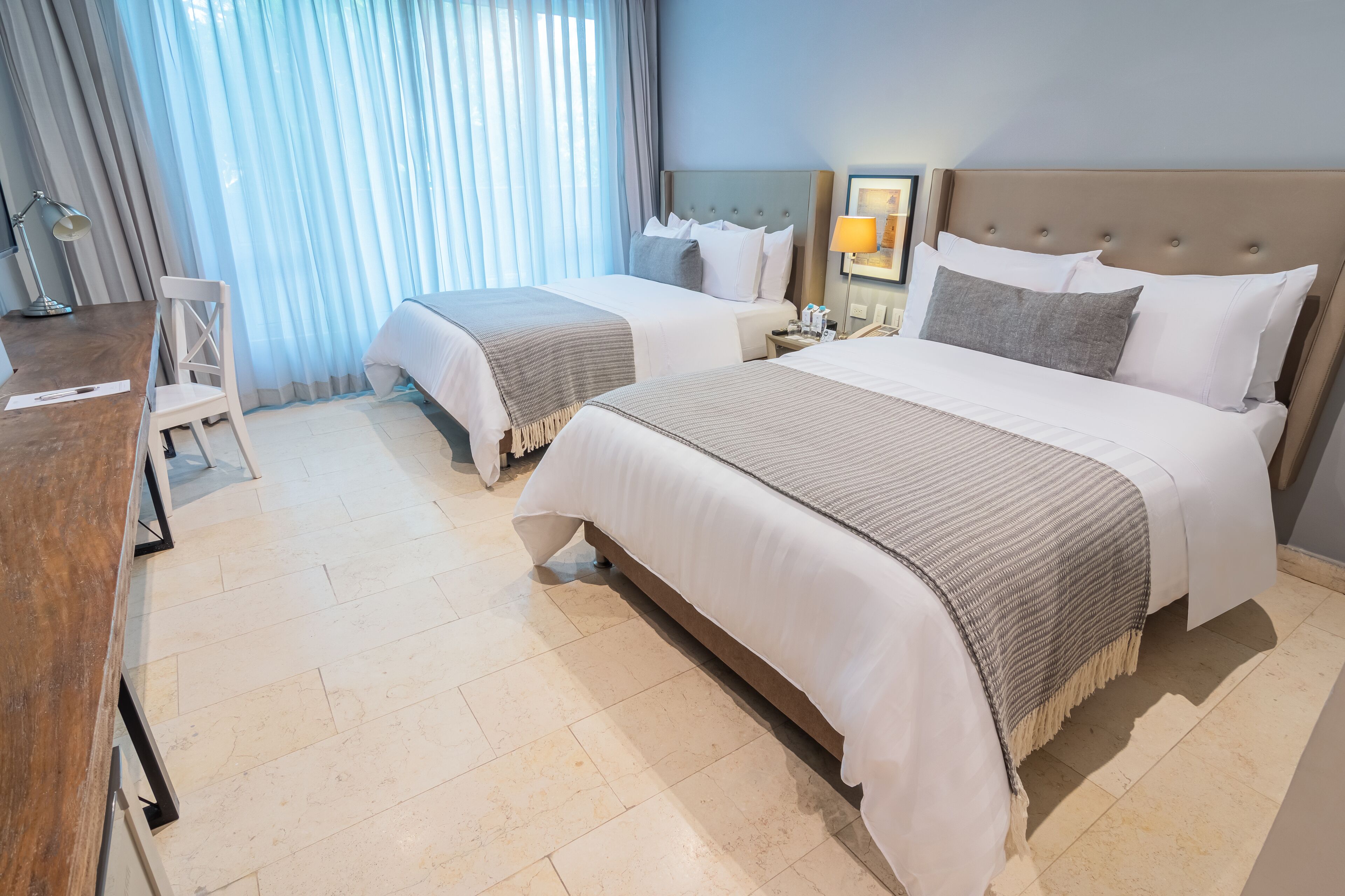 Une chambre d’hôtel avec deux lits, un bureau et une chaise.