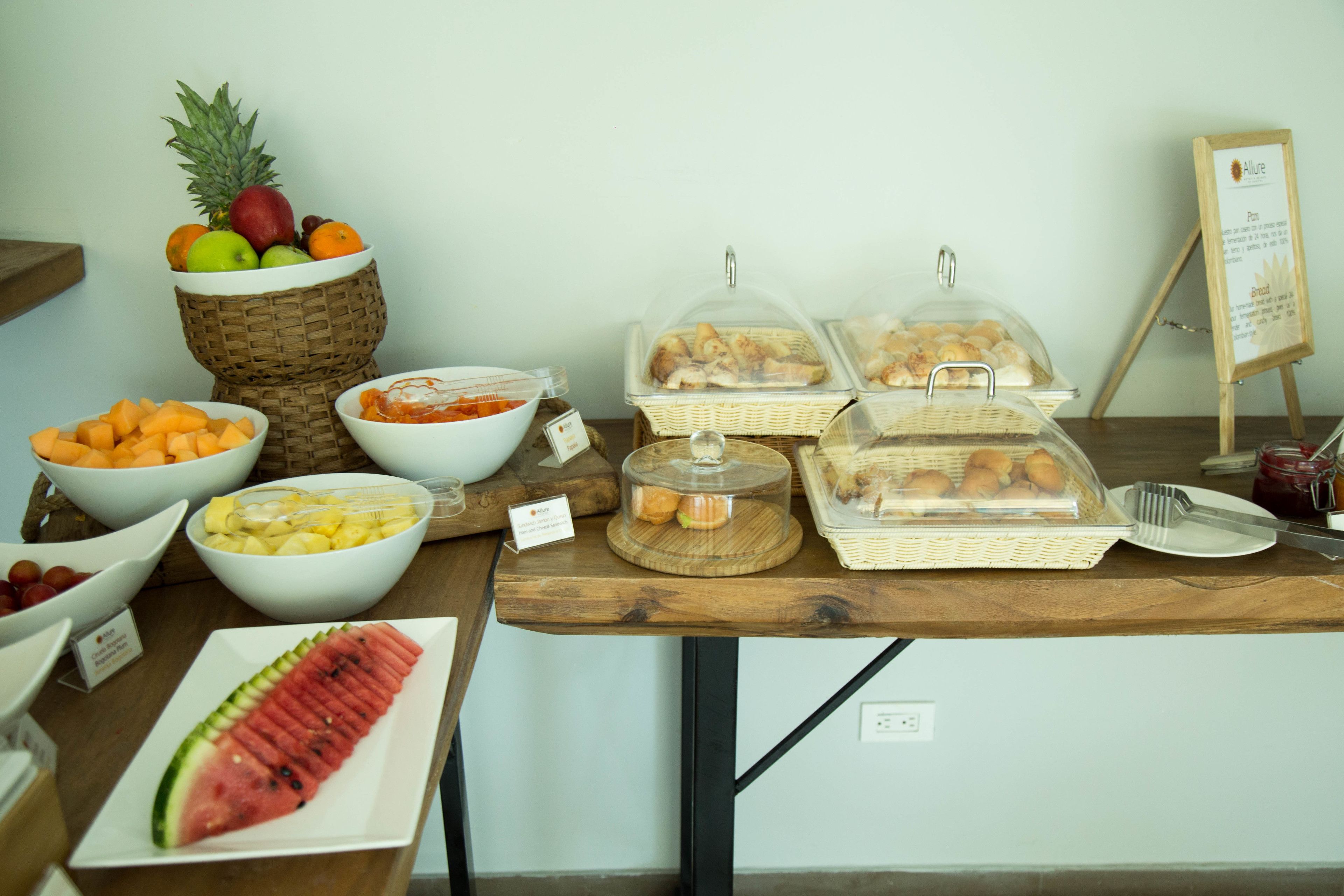 A buffet table with various food items including fruits, pastries, and bread.
