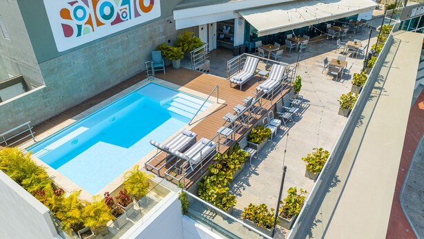 A rooftop pool area with lounge chairs, a pool, and a restaurant with outdoor seating. - GHL San Lazaro Art Hotel (Cartagena)