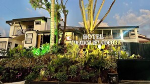 Un hotel de diseño moderno, con balcón y un jardín bien cuidado con diversas plantas.