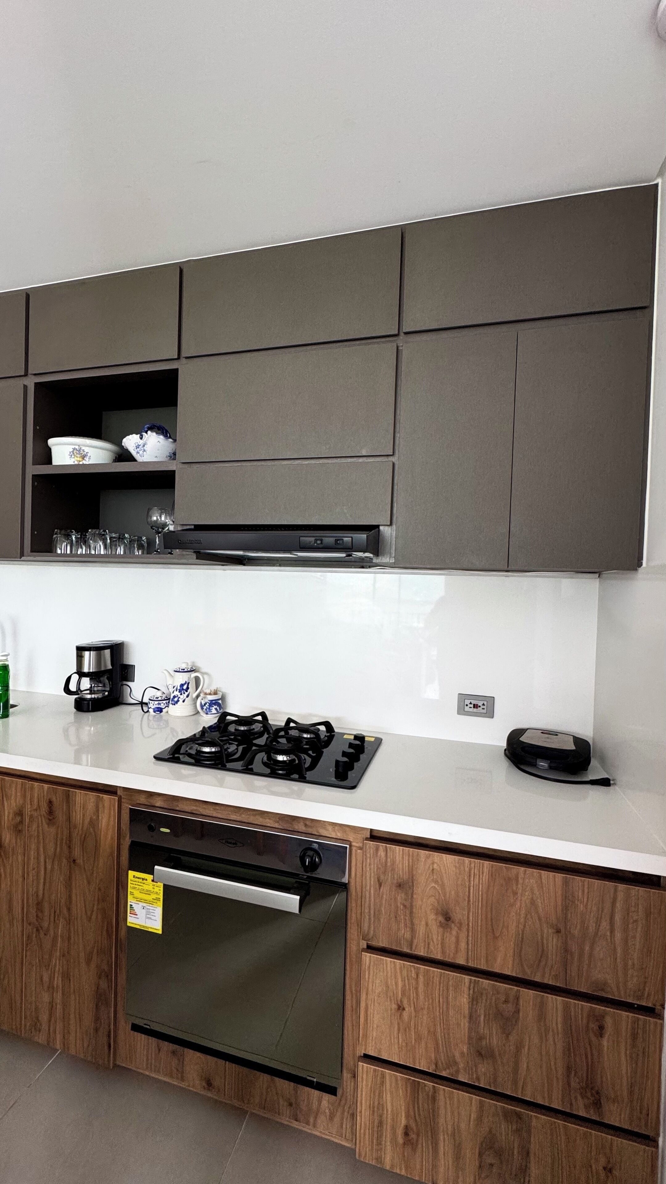 A modern kitchen with a gas stove, coffee maker, and wooden cabinets.