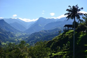 Un paisaje montañoso con un edificio solitario en una colina.