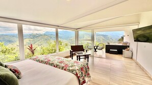 Un dormitorio con cama, escritorio, silla y vistas a las montañas.