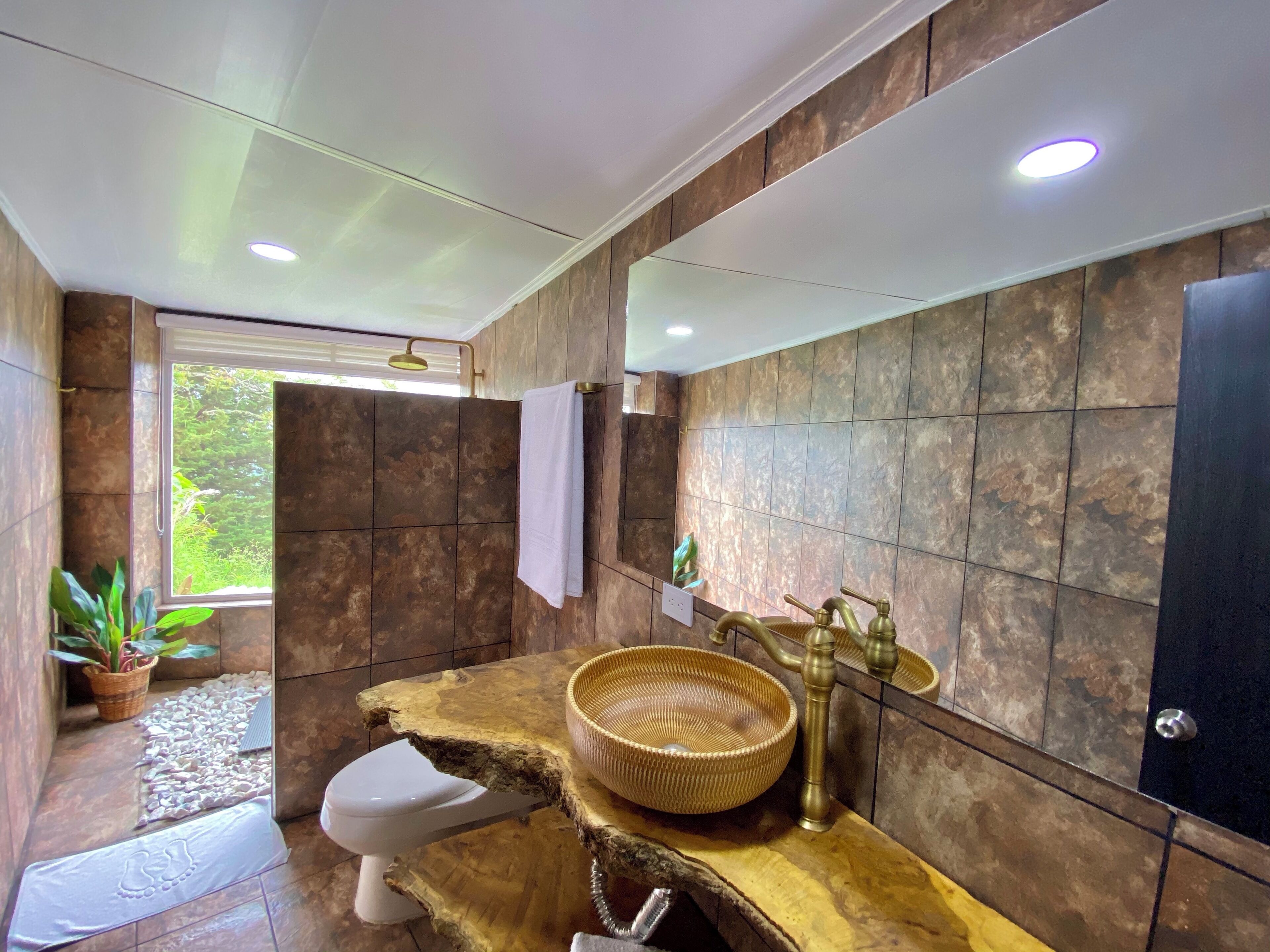 A bathroom with a wooden vanity, a white toilet, and a large mirror.