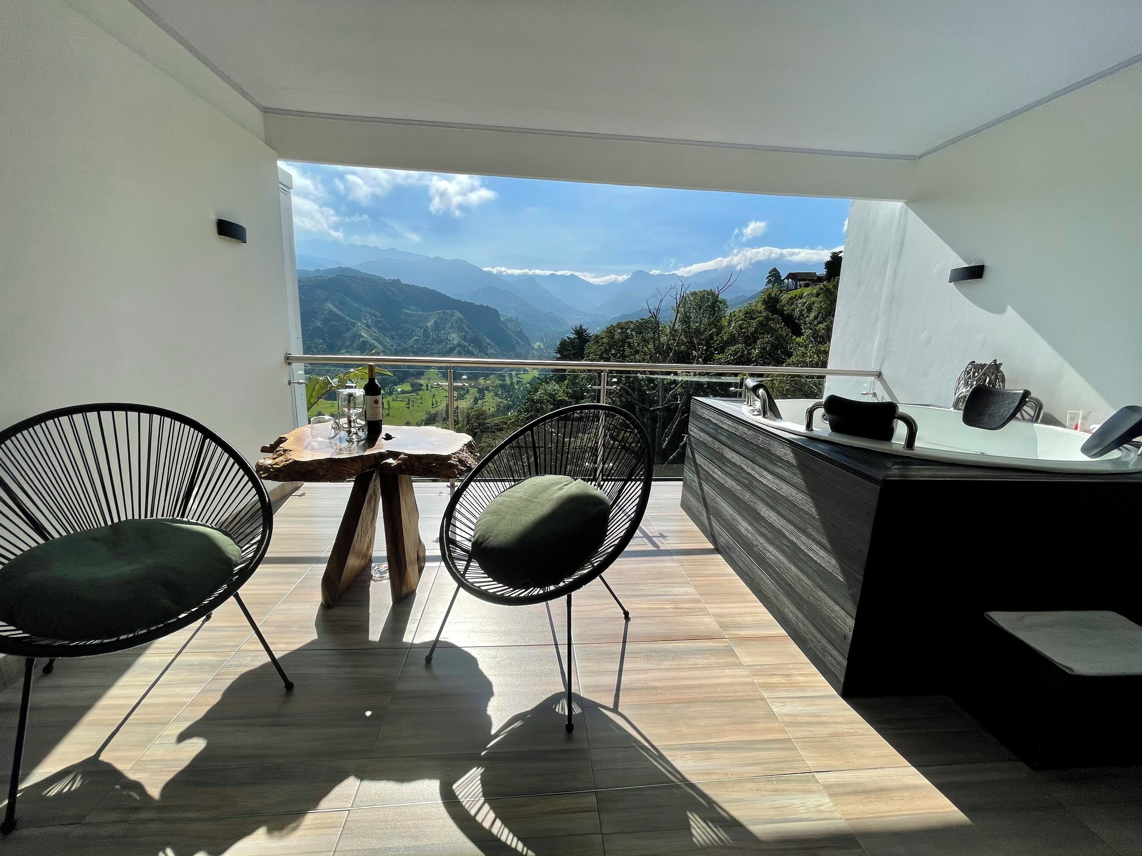 A balcony with two chairs, a table, and a bar area.