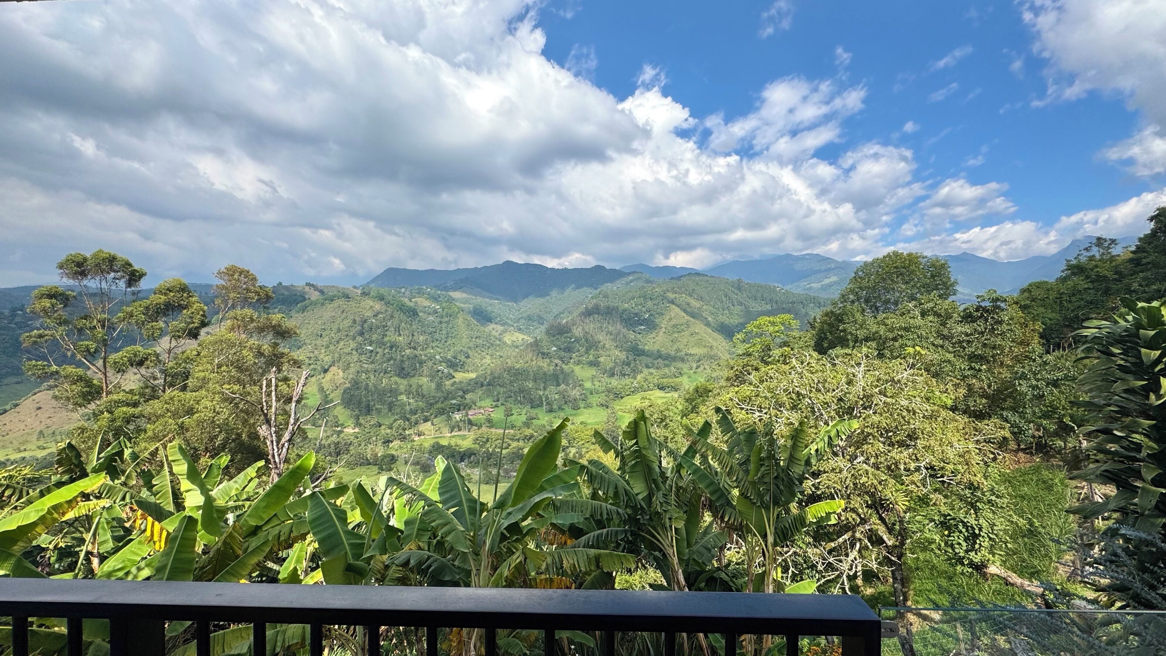 Un paysage magnifique, avec des collines et des montagnes verdoyantes sous un ciel partiellement nuageux.