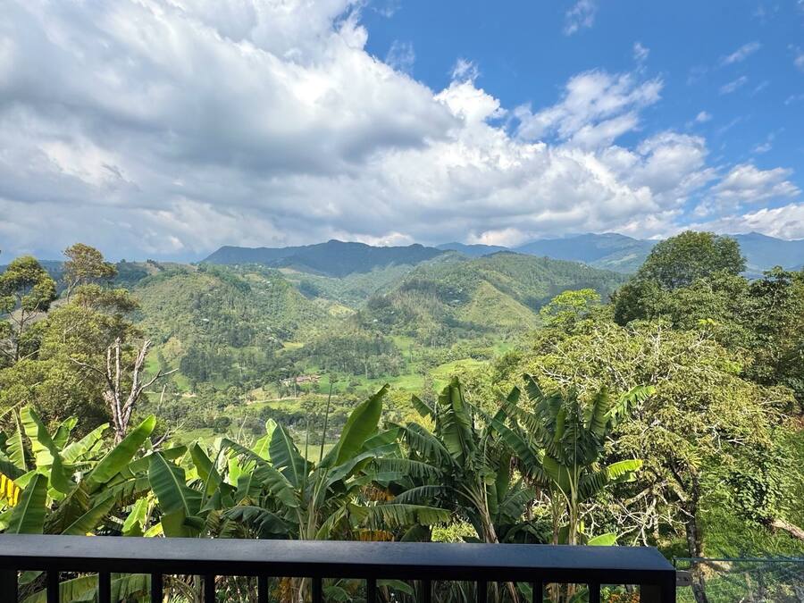 Un paysage magnifique, avec des collines et des montagnes verdoyantes sous un ciel partiellement nuageux.
